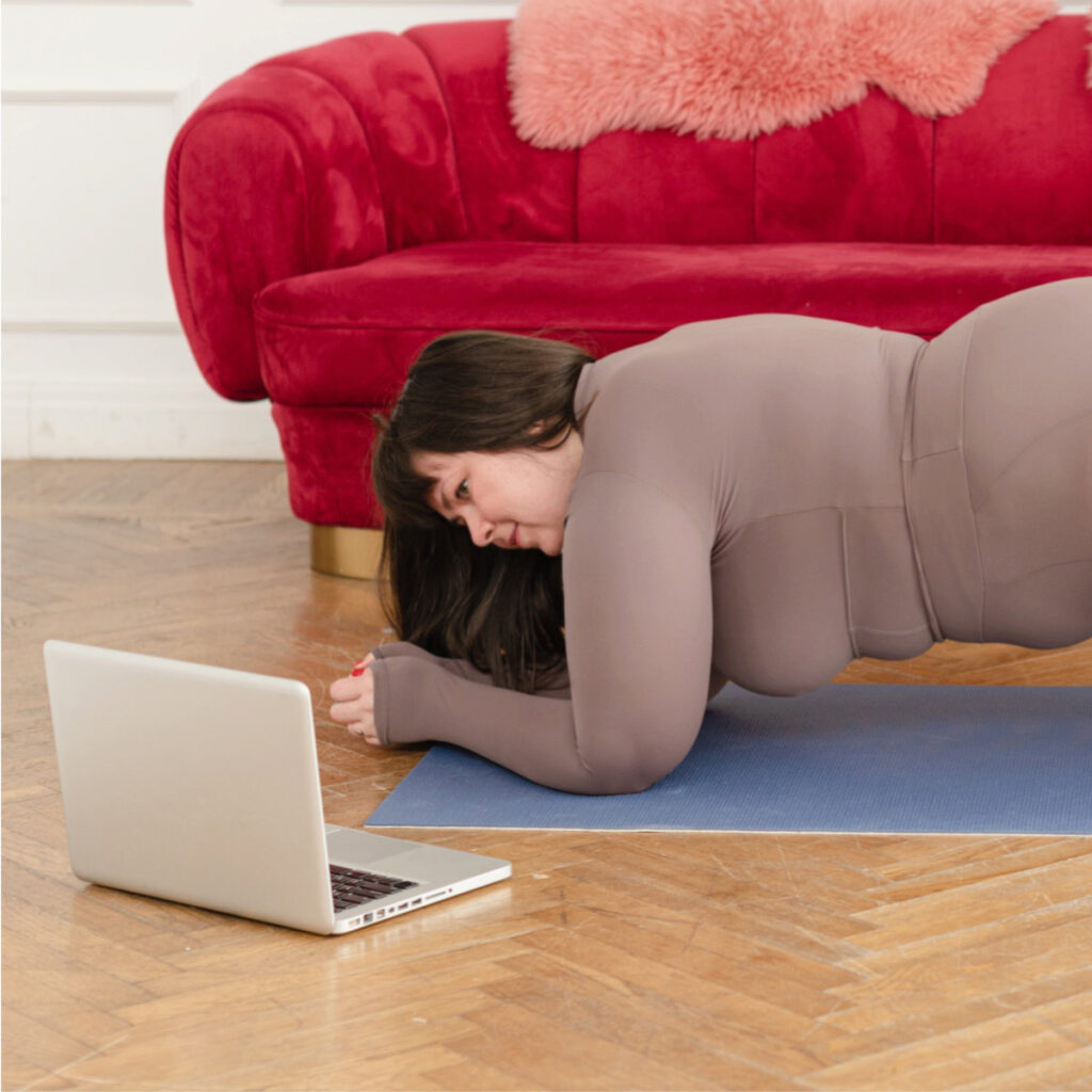 Woman doing yoga at home with recorded yoga video